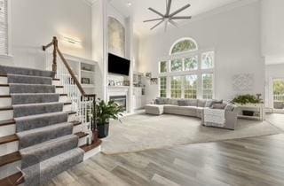 living room featuring stairs, ornamental molding, a fireplace, and wood finished floors