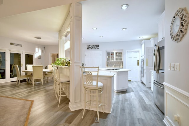 kitchen with light countertops, light wood-style flooring, smart refrigerator, white cabinetry, and a peninsula