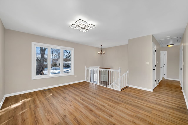 unfurnished room with baseboards, a notable chandelier, visible vents, and light wood finished floors