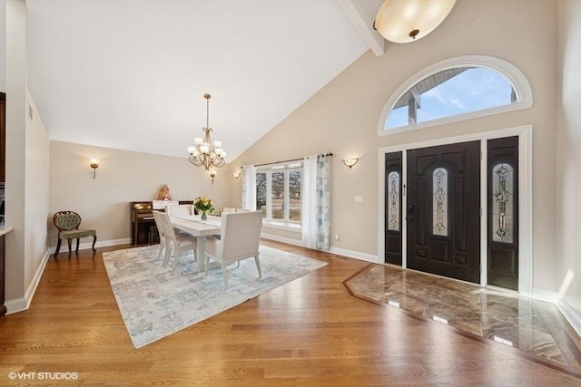 entryway with baseboards, beamed ceiling, an inviting chandelier, light wood-type flooring, and high vaulted ceiling