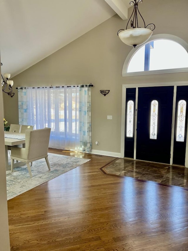 entrance foyer with baseboards, dark wood-type flooring, an inviting chandelier, high vaulted ceiling, and beam ceiling