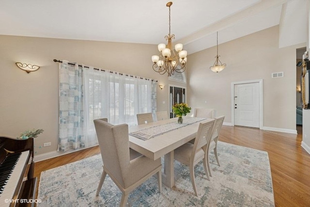 dining room with baseboards, high vaulted ceiling, visible vents, and light wood-style floors