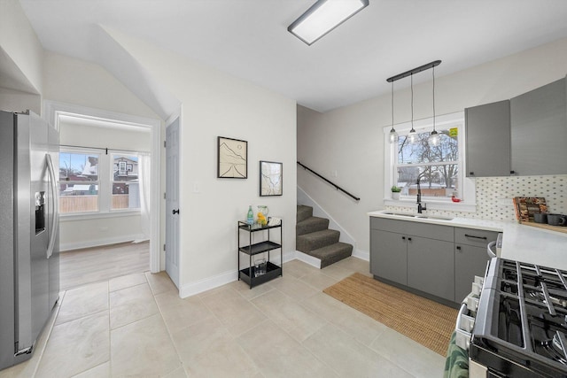 kitchen with tasteful backsplash, appliances with stainless steel finishes, hanging light fixtures, light countertops, and gray cabinetry