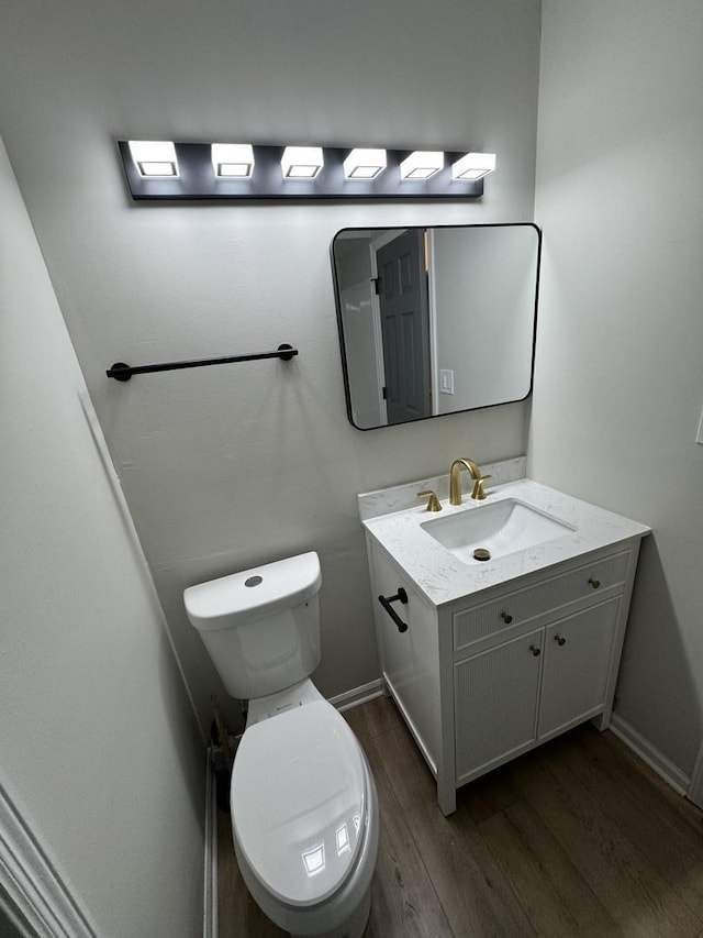 bathroom with baseboards, vanity, toilet, and wood finished floors