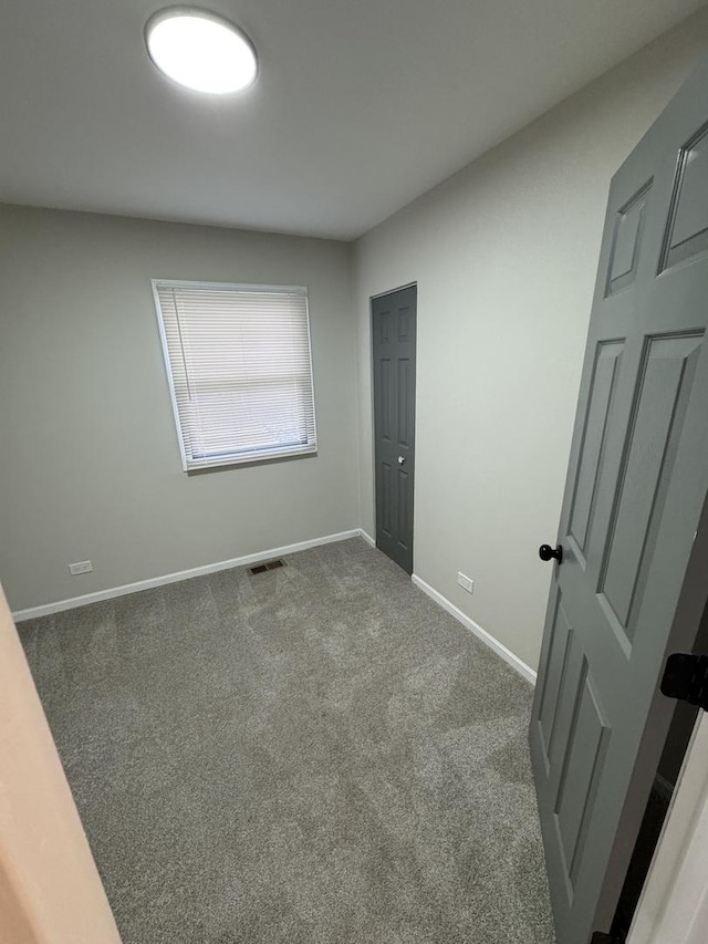 unfurnished room featuring baseboards, visible vents, and dark carpet