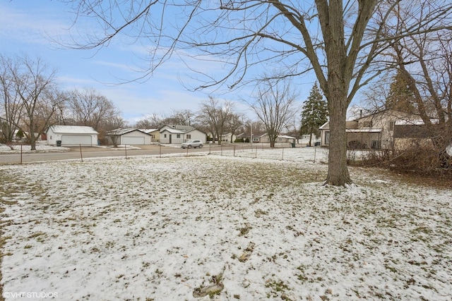 yard covered in snow with a garage, a residential view, and fence