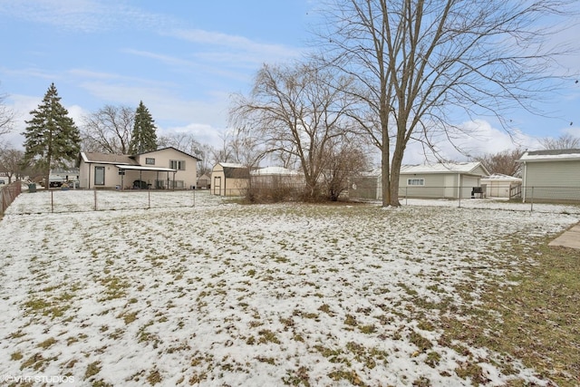 yard covered in snow with a residential view and fence