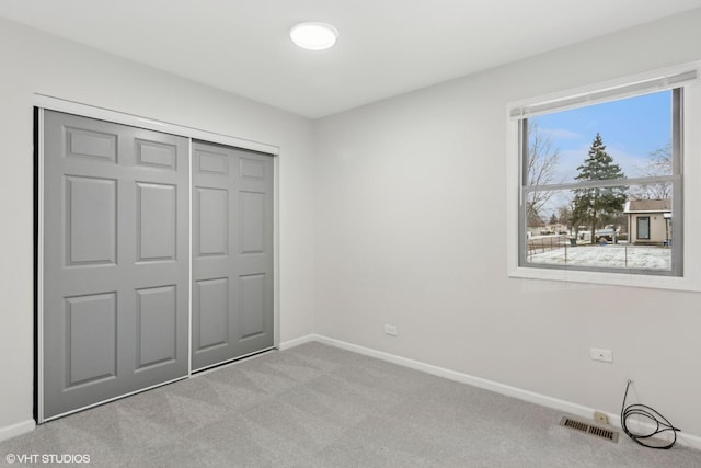 unfurnished bedroom with baseboards, a closet, visible vents, and light colored carpet