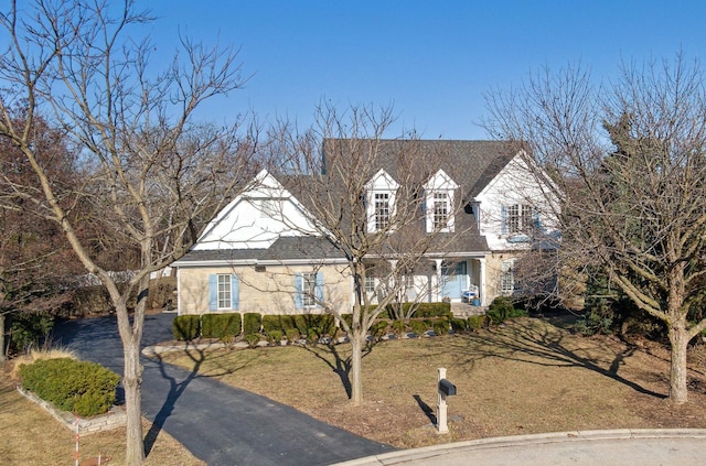 cape cod home with driveway and a front lawn