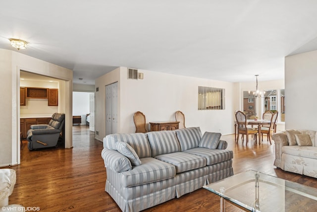 living room with dark wood-style flooring, visible vents, and a notable chandelier