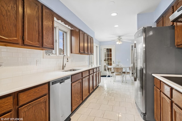 kitchen with stainless steel appliances, light countertops, decorative backsplash, a sink, and under cabinet range hood