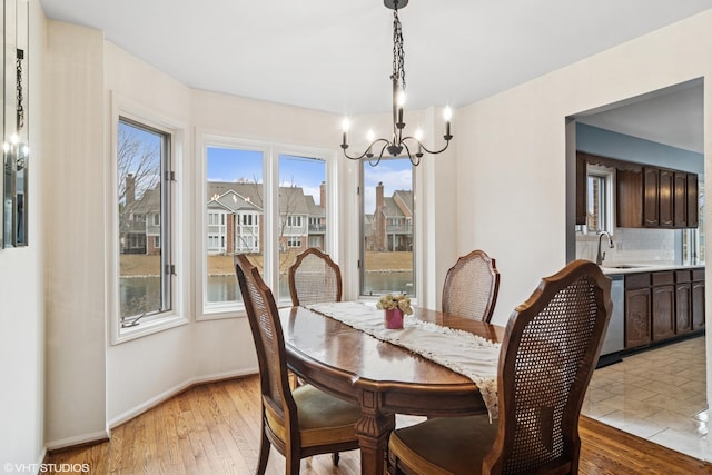 dining room featuring baseboards, light wood finished floors, and an inviting chandelier