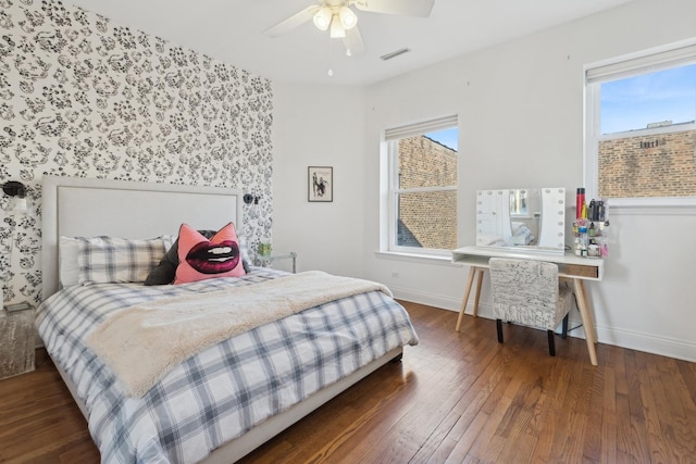 bedroom featuring a ceiling fan, wood finished floors, visible vents, and baseboards