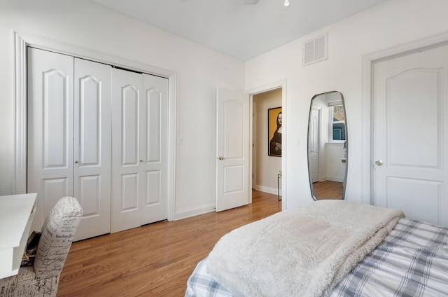 bedroom featuring light wood-type flooring, a closet, visible vents, and baseboards