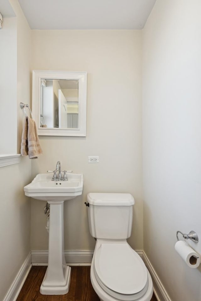 half bath featuring toilet, baseboards, and wood finished floors