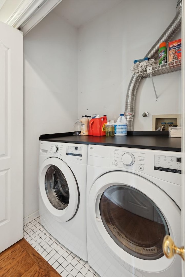 laundry room with laundry area, washer and clothes dryer, and light tile patterned flooring