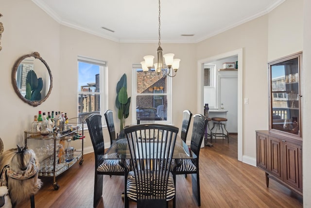 dining room with a notable chandelier, crown molding, baseboards, and wood finished floors