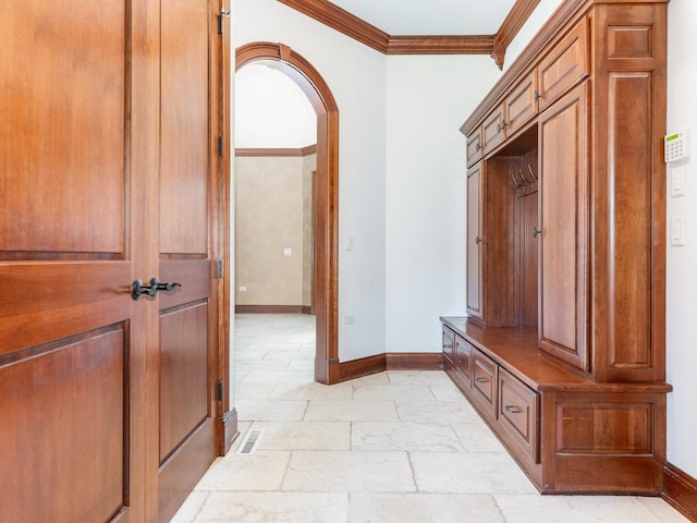 mudroom featuring baseboards, arched walkways, stone tile floors, and crown molding