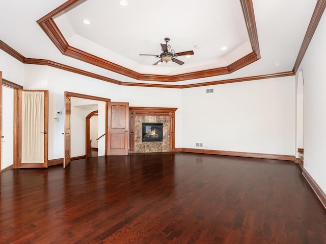 unfurnished living room featuring a tray ceiling, visible vents, ceiling fan, wood finished floors, and baseboards