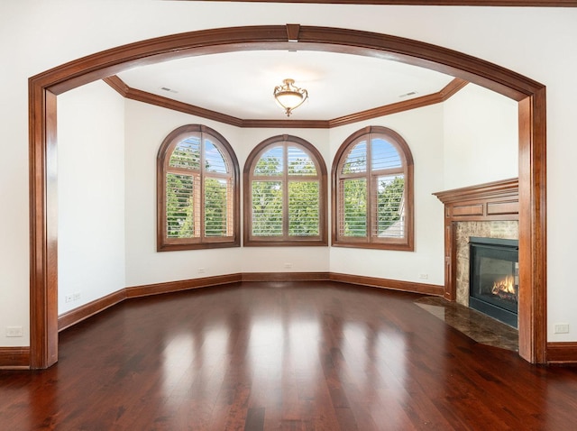 unfurnished living room with a fireplace, crown molding, baseboards, and wood finished floors