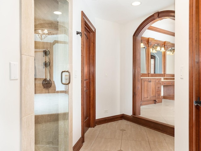 hallway with tile patterned flooring, arched walkways, baseboards, and recessed lighting