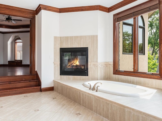 bathroom with baseboards, ornamental molding, a bath, tile patterned floors, and a glass covered fireplace