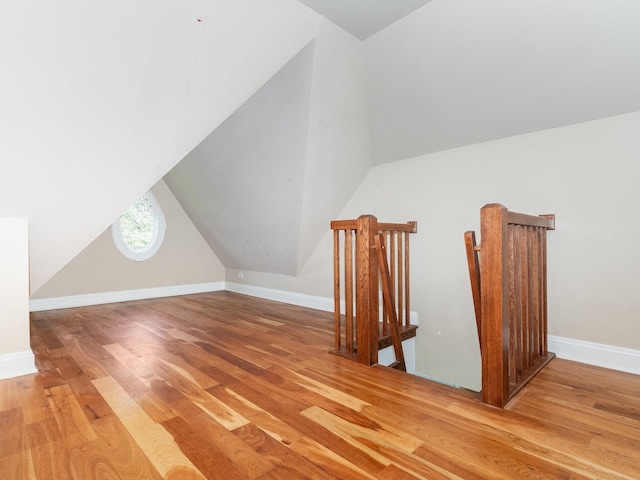 additional living space featuring baseboards, vaulted ceiling, and wood finished floors