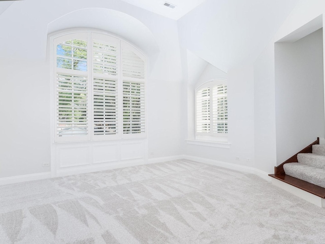 carpeted empty room featuring stairs, visible vents, and baseboards