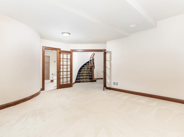 empty room featuring french doors, light colored carpet, visible vents, baseboards, and stairs