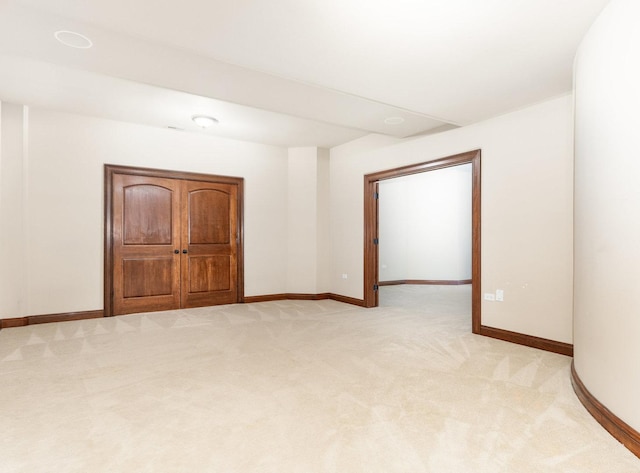 unfurnished room with light colored carpet and baseboards