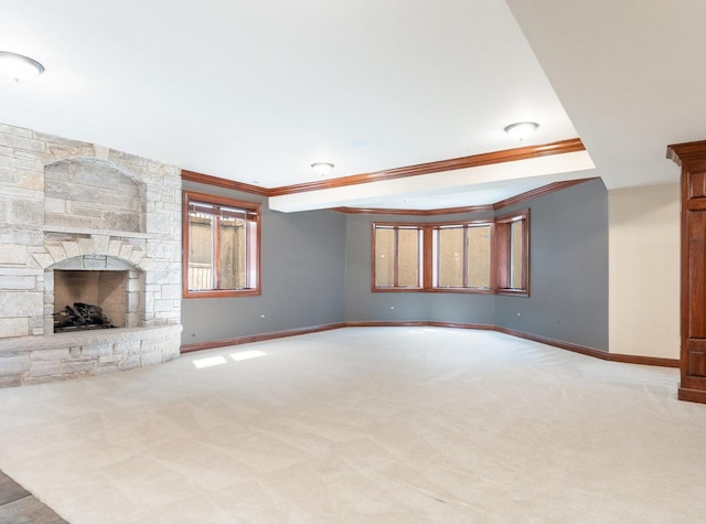 unfurnished living room with crown molding, a fireplace, baseboards, and carpet flooring