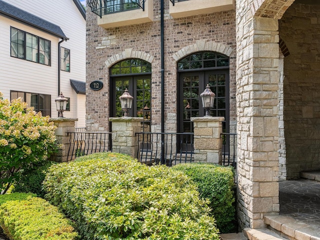 entrance to property with french doors, brick siding, and a balcony