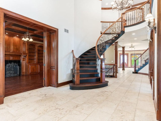 stairs with baseboards, built in features, visible vents, and an inviting chandelier