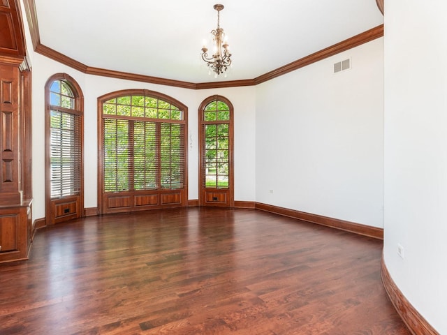 spare room featuring a notable chandelier, visible vents, baseboards, ornamental molding, and dark wood finished floors