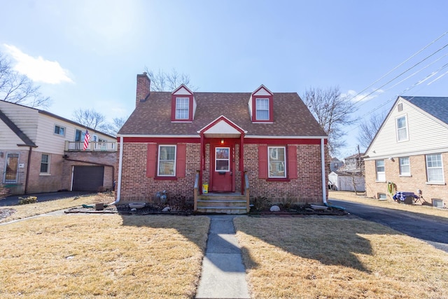 view of front of property featuring brick siding, a chimney, a front lawn, and roof with shingles