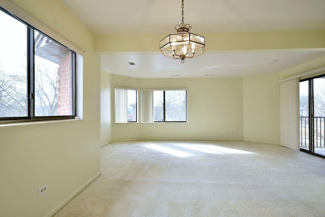 empty room with light carpet, baseboards, visible vents, and a chandelier