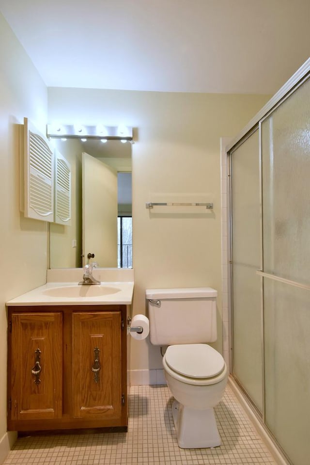 bathroom with a shower with door, vanity, toilet, and tile patterned floors