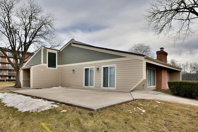 rear view of property featuring a patio, a chimney, and a lawn