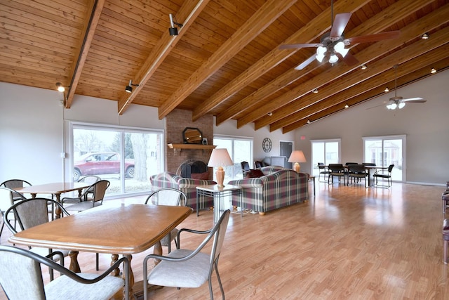 dining room featuring a brick fireplace, wood ceiling, plenty of natural light, and light wood-style floors