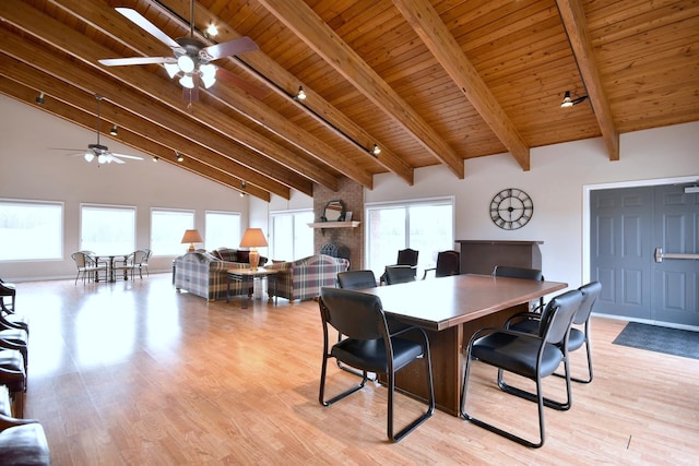 dining room featuring track lighting, a fireplace, wooden ceiling, and light wood-style floors