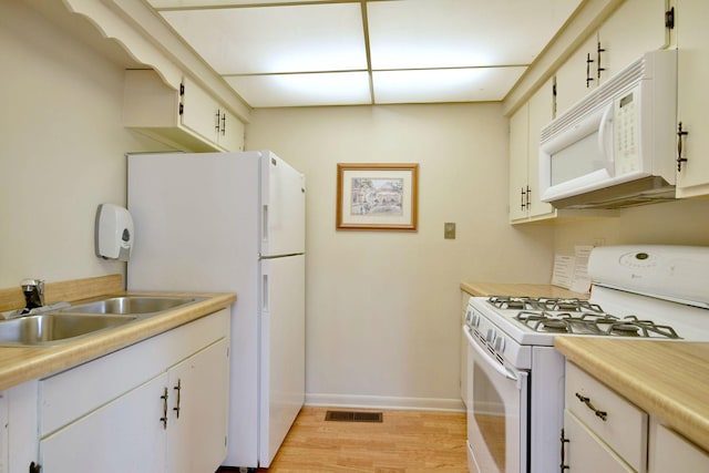 kitchen with white appliances, light countertops, a sink, and light wood-style flooring