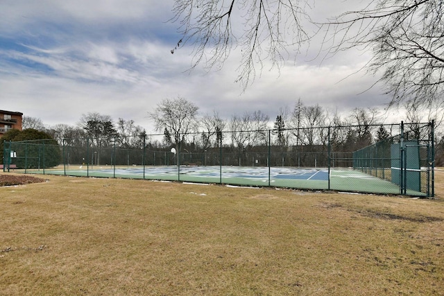 view of tennis court featuring a lawn and fence