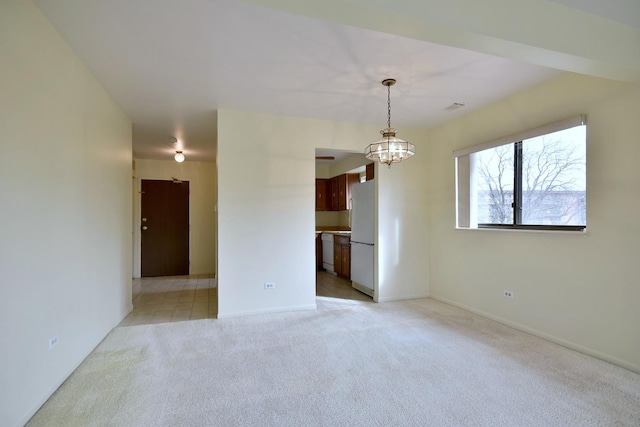 empty room featuring light carpet, baseboards, and an inviting chandelier