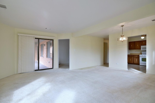 unfurnished living room featuring light colored carpet, visible vents, and ceiling fan with notable chandelier