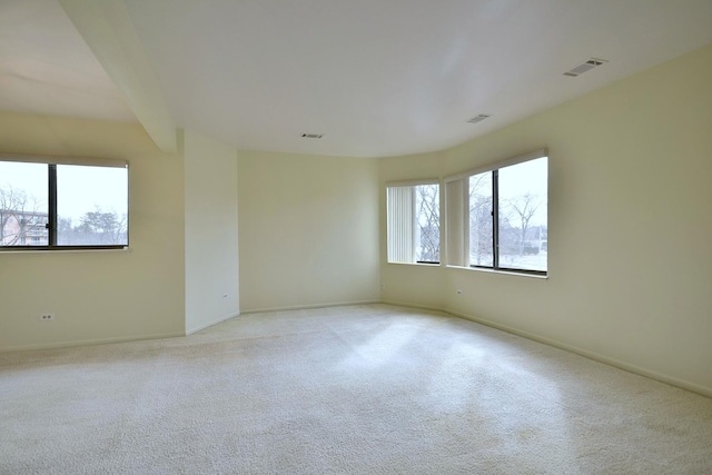 spare room with a healthy amount of sunlight, visible vents, and light colored carpet