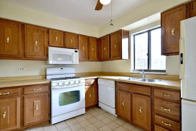 kitchen featuring white appliances, light countertops, a sink, and brown cabinetry