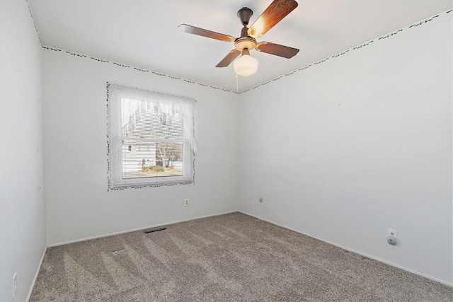 empty room featuring a ceiling fan, light colored carpet, and visible vents