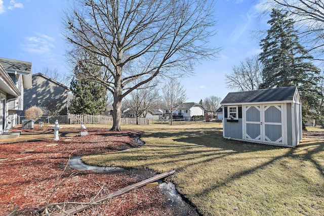 view of yard with an outbuilding, fence, and a storage shed