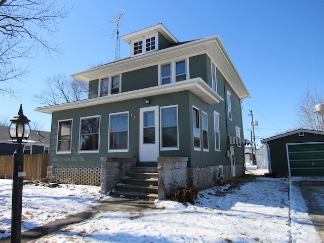 american foursquare style home featuring entry steps, fence, and an outbuilding