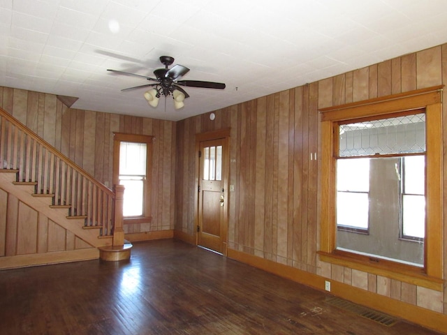 interior space with a healthy amount of sunlight, stairs, visible vents, and dark wood-type flooring